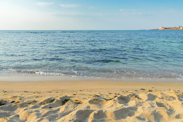 sunny morning scenery at the sea. calm waves washing the sandy beach. transparent water and bright blue sky