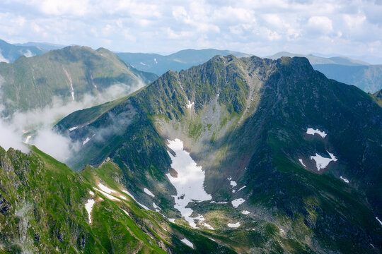 wonderful summer mountain scenery. fagaras range of romania. sunny morning. rocky cliffs and clouds. beautiful green countryside