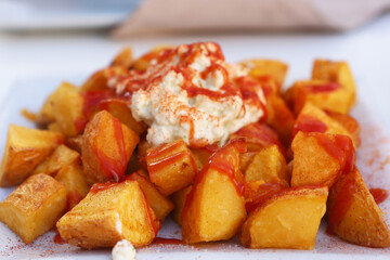 baked potato with garlic sauce aioli and tomato ketchup on square plate with human hands closeup photo