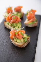 Salmon trout bruschetta on bread pieces with avocado and micro greens snack food