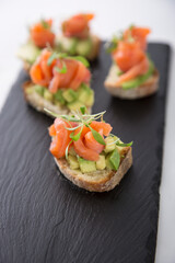Salmon trout bruschetta on bread pieces with avocado and micro greens snack food
