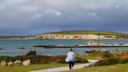 Obraz premium women walking down the path on the coast showing the cliffs and green grass.