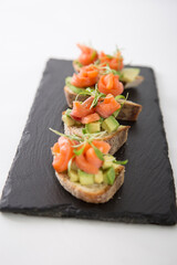 Salmon trout bruschetta on bread pieces with avocado and micro greens snack food