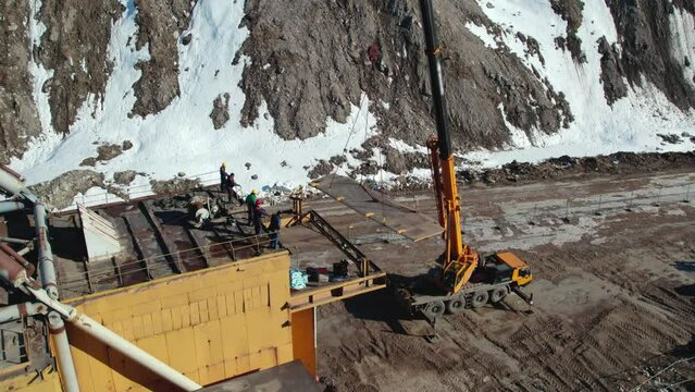 Industrial crane lifting dragline excavator part. Civil engineering deconstruction project in quarry. Precious metal mining with heavy machinery concept.