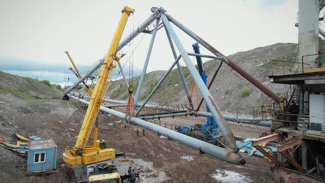Multiple cranes lifting dragline excavator boom. Civil engineering deconstruction project in quarry. Precious metal mining with heavy machinery concept.