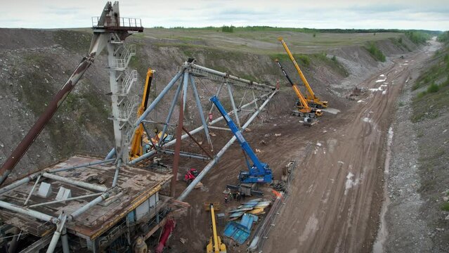 Multiple cranes lifting dragline excavator boom. Civil engineering deconstruction project in quarry. Precious metal mining with heavy machinery concept.