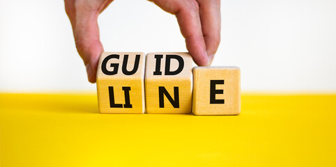 Guideline symbol. Concept word Guideline on wooden blocks. Businessman hand changes words Guide on Line. Beautiful yellow table white background. Business and guideline concept. Copy space.