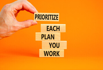 Prioritize each plan you work symbol. Concept words Prioritize each plan you work on blocks on beautiful orange background. Businessman hand. Business prioritize each plan you work concept. Copy space