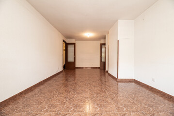 empty room with reddish stoneware floor, matching baseboard, white walls and dark wood carpentry on the doors