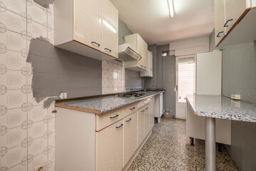 Kitchen with old wooden furniture, half-painted walls and terrazzo floors