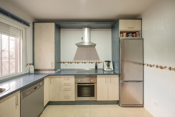 Fototapeta na wymiar Front image of a kitchen with wooden furniture, integrated stainless steel appliances and blue countertop