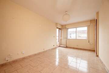 Empty room with pale pink painted walls and stoneware floors of the same color with windows and access to a terrace