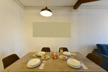 Rectangular wooden dining table with designer chairs upholstered in brown velvet, glass bowl with fruit and ducks with biscuits and desserts