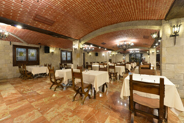 Dining room with vaulted rustic brick ceilings with wooden tables with white tablecloths and matching chairs