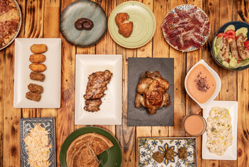 Set of fast food dishes and typical Spanish tapas, alioli potatoes, acorn-fed ham tray, assorted croquettes, Galician empanada, salmorejo with croutons, roast chicken and oven-roasted ribs