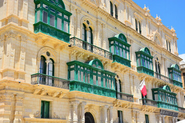 Traditional green balconies, Maltese architecture and national flag in Valetta, Malta