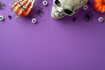 Halloween creepy decorations concept. Top view photo of skull skeleton hand holding pumpkin...