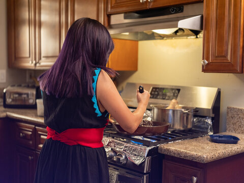 Indigenous woman smashing beans in an indoor kitchen