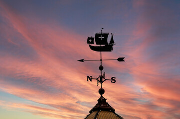 Silhouette of weathervane at sunset. The weathervane is a Spanish ship under full sail. - obrazy, fototapety, plakaty