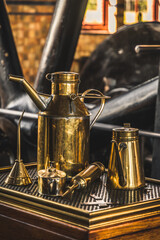 Old brass oil cans for lubricating machines. Turbine in the background.