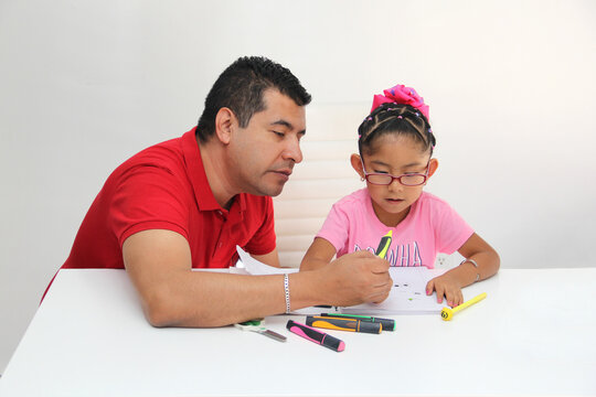 Latino dad and daughter, teacher and student draw in a notebook with colors in this back to school to improve skills with Autism Spectrum Disorder (ASD)