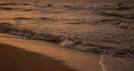 The sandy shore of the Sea of Azov at sunset, a warm summer evening, the waves are beating against...