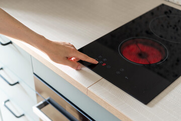hand press button on electric stove in kitchen