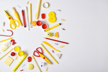 Various red and yellow stationery items lie in the shape of a heart on a white background.