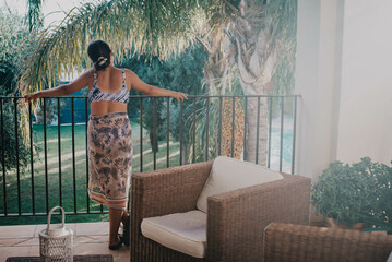 Piękna dziewczyna stoi na balkonie w pokoju hotelowym na widokiem na basen