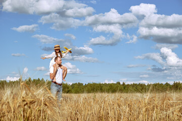 A young man plays with his daughter in a rye field on a sunny day. A man holds a child in his arms....