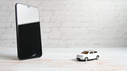 スマートフォンの横に自動車ミニカーを置いた木製背景の動画
