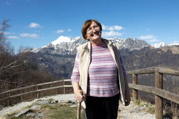 Naklejka premium Smiling Senior Woman on an Alpine Viewpoint on a Journey on Fresh Air in Mountains