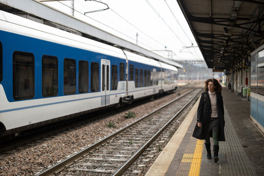 Woman with a Coat Walking on an Empty train Station in Italy