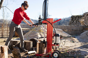 Female Worker in Red Cloths Cut Firewood with an Electric Splitter for Winter Heating