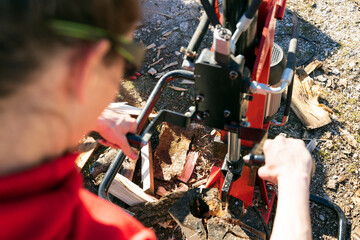 Close Up of a Female Worker in Red Cloths Cut Firewood with an Electric Splitter for Winter Heating