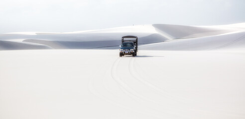 offroad car driving through the white sand dunes of Lencois Maranhenses  