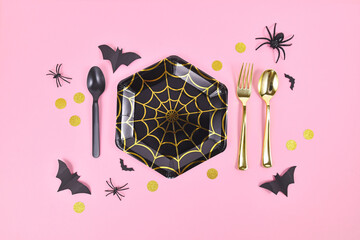 Halloween party paper plate with spider web and seasonal decoration on pink background