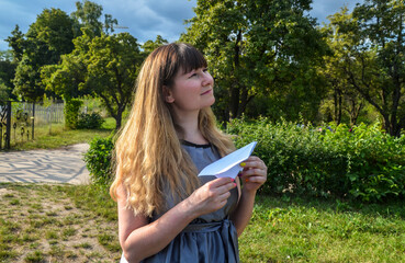 Young girl with paper plane in the hand dreaming about travel, a symbol of the dream, wish