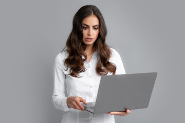 Pretty assistant holding notebook search information internet. Young business woman with laptop computer isolated studio portrait on gray background. Freelancer at work.