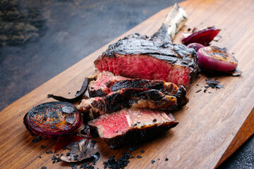 Traditional barbecue dry aged Kobe tomahawk steak with grilled onions served as close-up on a...