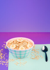 Plate of natural oatmeal with bananas and a glass of fresh milk with a pastel colored background, copy paste