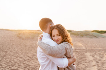 Young family couple hugging on the beach at sunset time, happy l