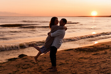 Silhouette of a couple of young lovers hugging on the beach duri