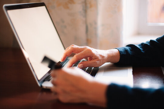 Close up of mature woman using laptop computer and credit card at home