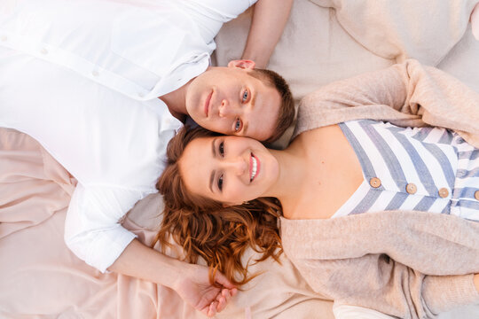 A young couple in love in the evening on the beach  lie on a bla