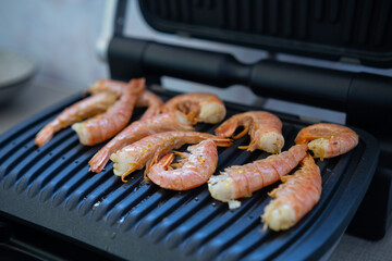 Cooking fresh large shrimp on an electric grill. Picnic on the balcony