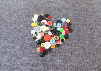 Colored buttons and a pin on a gray fabric. Buttons close up.