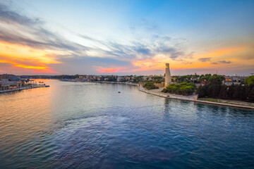 The Italian Sailor Monument can be seen along with the seaside port city of Brindisi, Italy, at sunset. Viewed from a cruise ship at sea in the Puglia region of Italy.