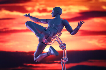 Male figurine posing as superhero swinging in front of blurred red cloudy sky.