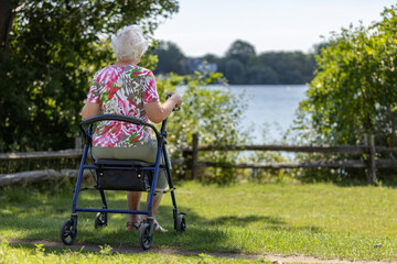Old woman walking outside with a rollator - 525953259